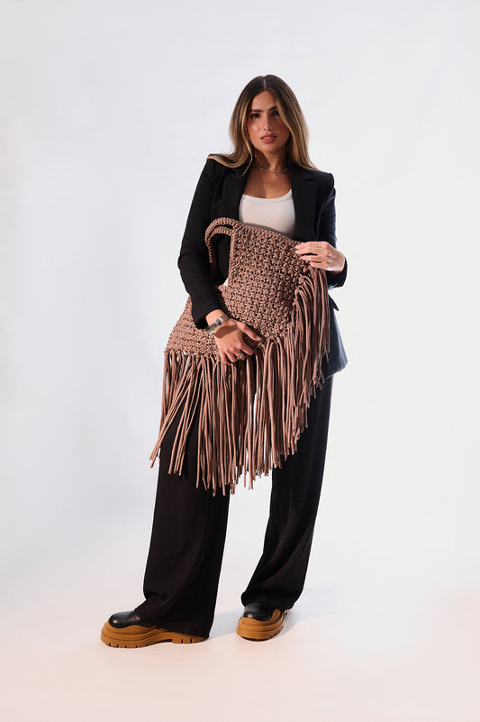 Woman holding a brown fringed bag against a white background