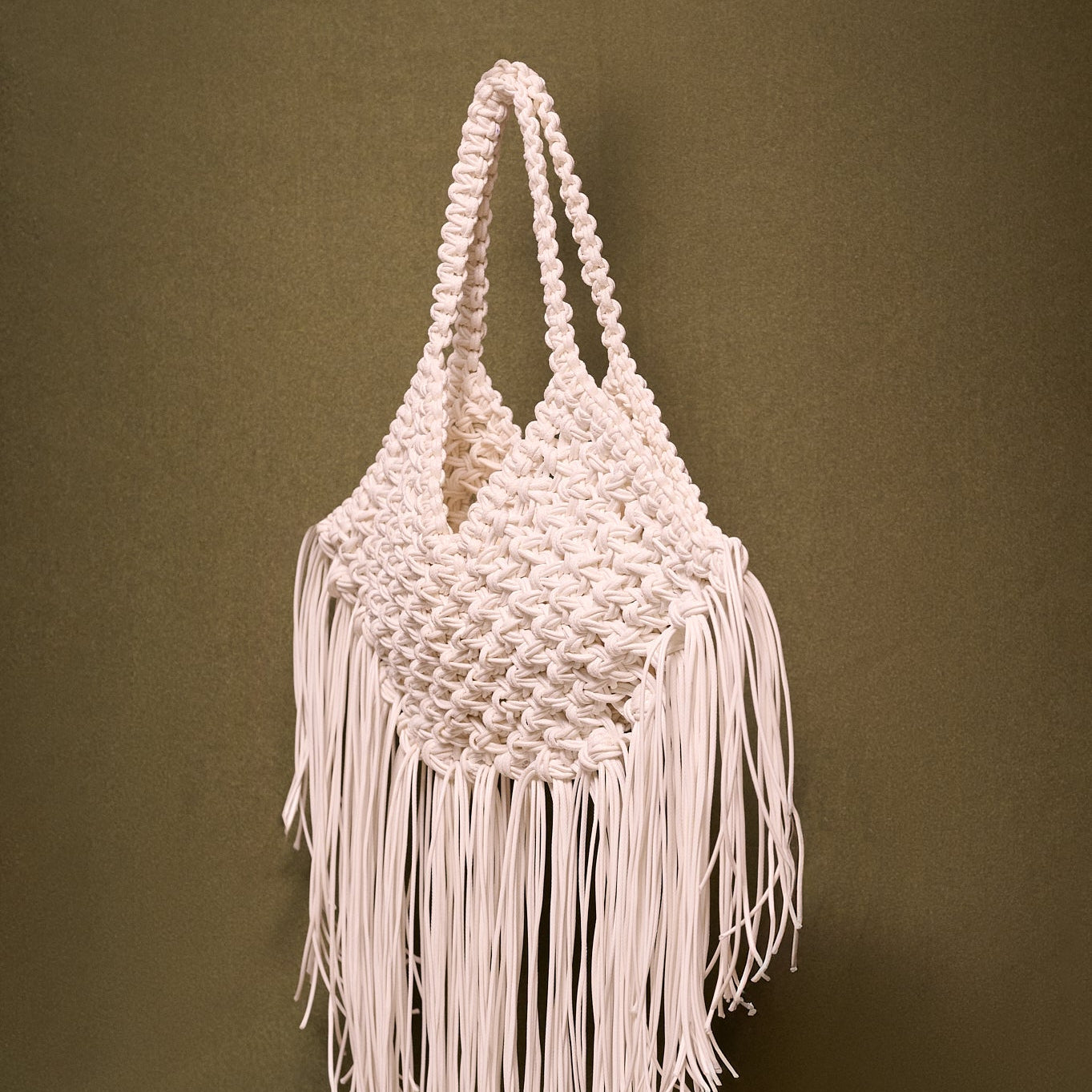 Macrame bag with fringes on a olive background