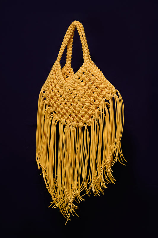 Yellow woven handbag with fringe on a blue background