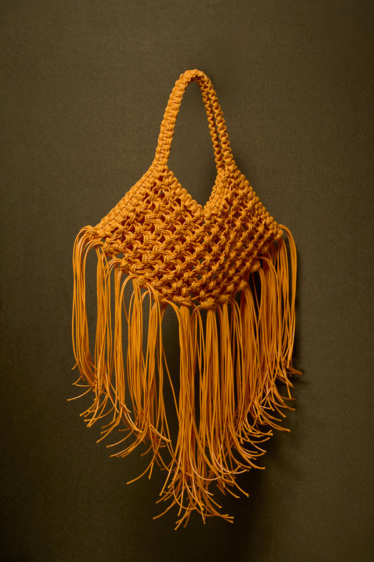Yellow mustard woven bag with fringes on a dark oilvebackground
