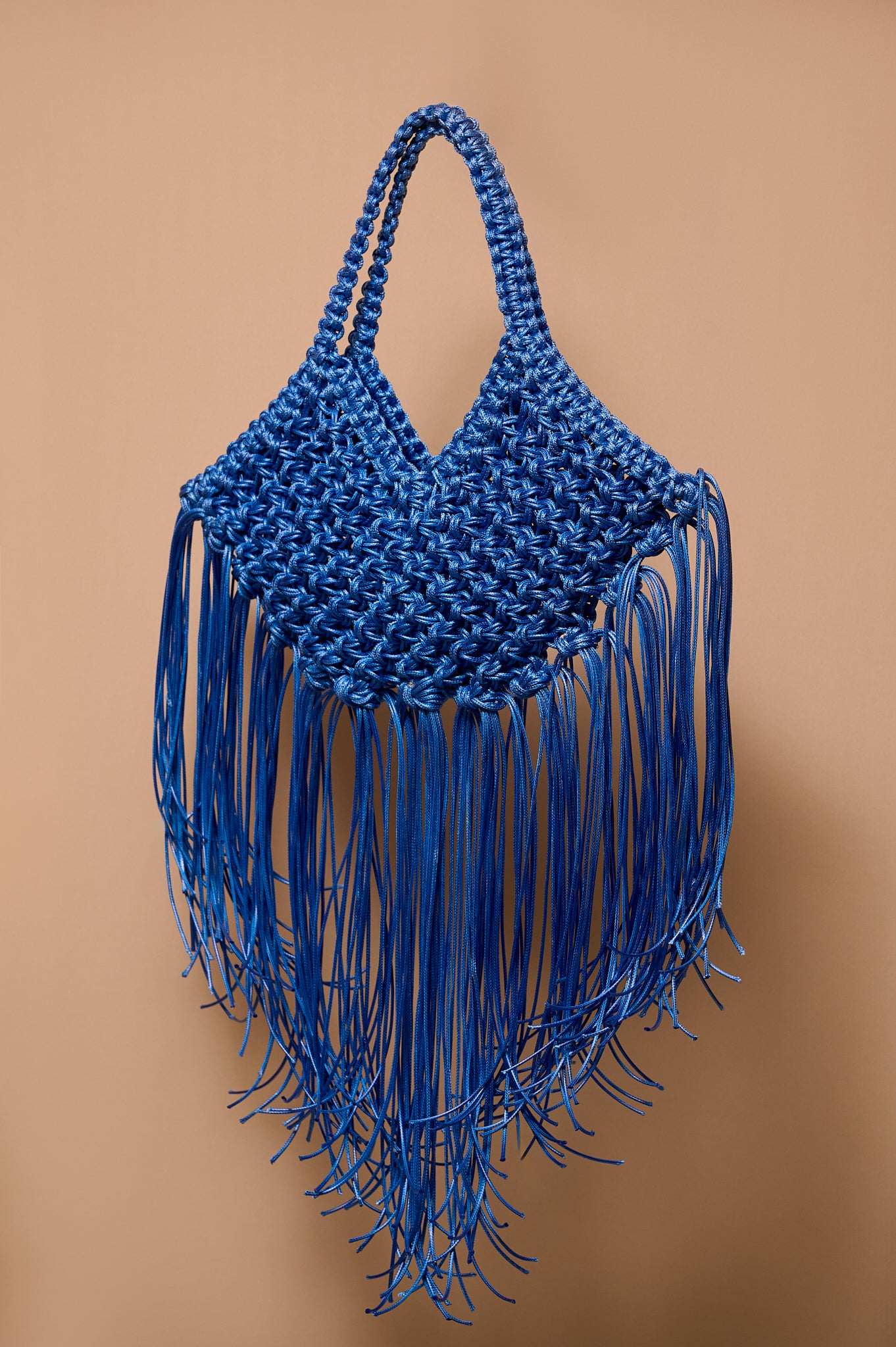 Blue woven handbag with fringe on a brown background