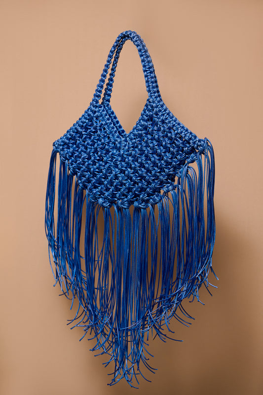 Blue woven handbag with fringe on a brown background