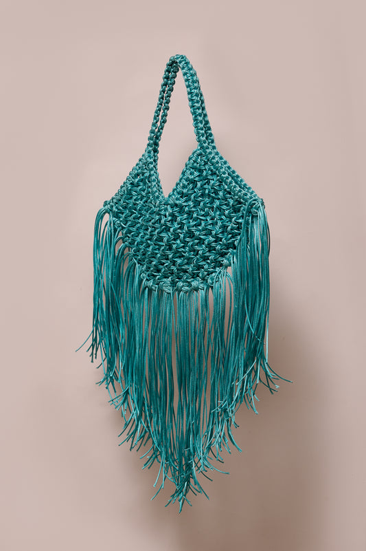 Teal macrame bag with fringes on a beige background